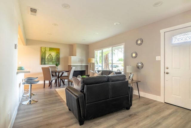 living room with light wood-style flooring, baseboards, visible vents, recessed lighting, and a fireplace