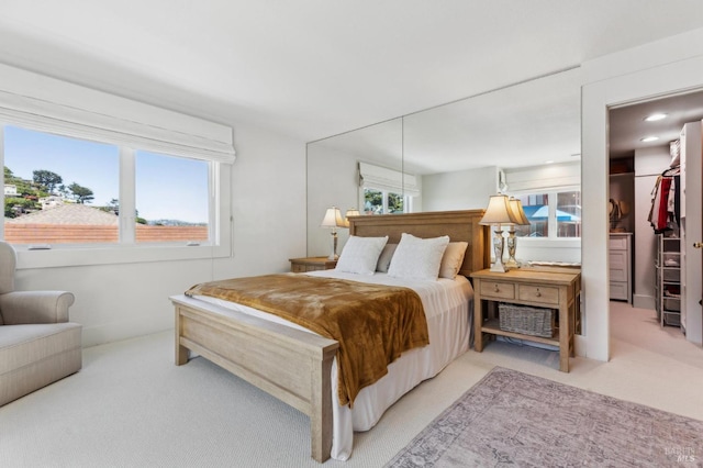 bedroom with a walk in closet and light carpet
