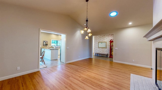 unfurnished living room with a tiled fireplace, baseboards, light wood-style floors, lofted ceiling, and recessed lighting