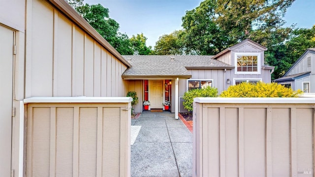 property entrance with a shingled roof and board and batten siding