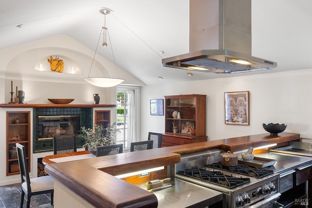 kitchen with a tiled fireplace, stainless steel range with gas stovetop, vaulted ceiling, and island exhaust hood