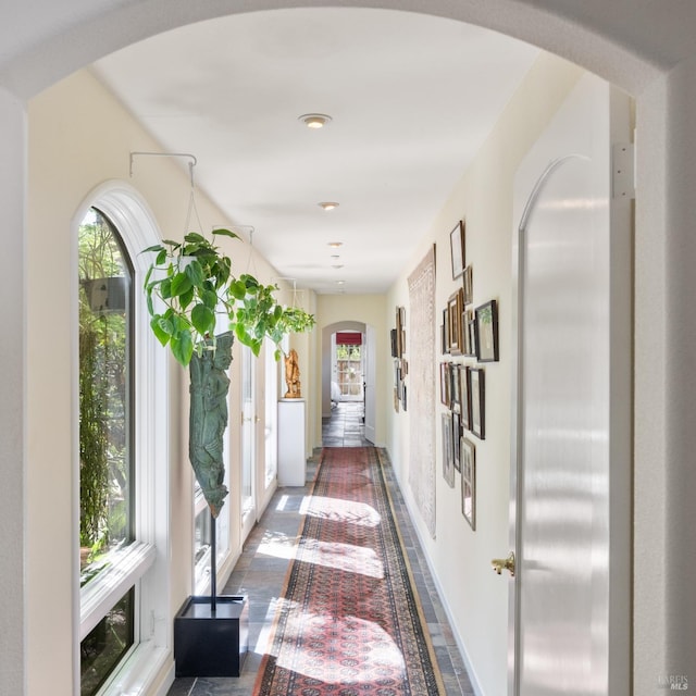 hall with arched walkways, french doors, and baseboards