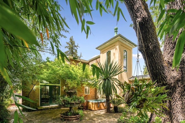 exterior space featuring stucco siding, a hot tub, a patio area, and french doors