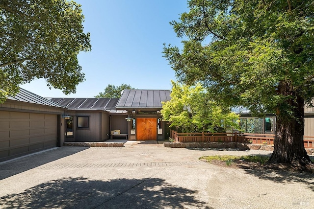 contemporary home featuring a standing seam roof, fence, metal roof, a garage, and aphalt driveway