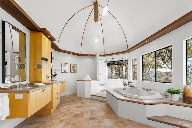 bathroom with stone finish flooring, a garden tub, vanity, and recessed lighting