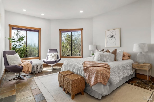 bedroom featuring recessed lighting, stone tile floors, and multiple windows