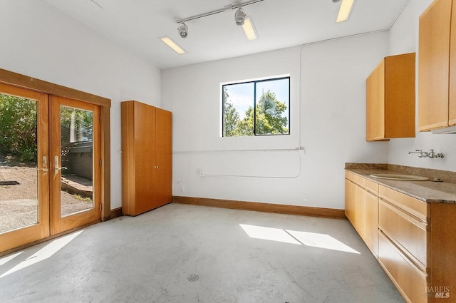 unfurnished dining area featuring french doors, concrete flooring, a sink, and a healthy amount of sunlight