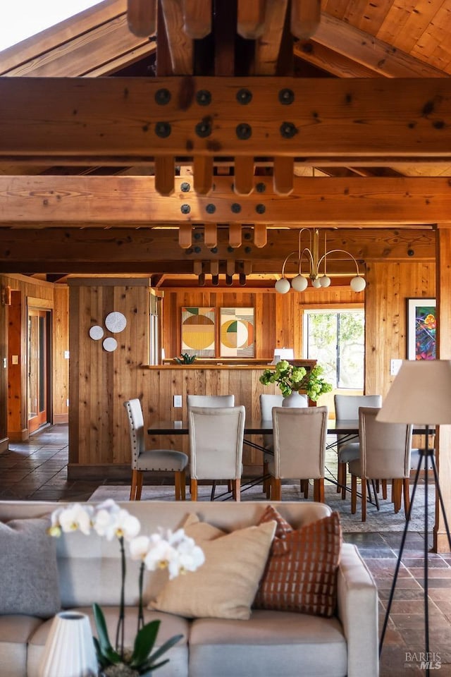 living room featuring lofted ceiling with beams, wood walls, and a chandelier