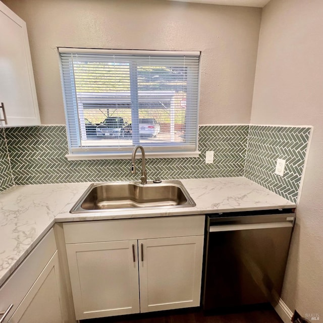 kitchen with a sink, backsplash, white cabinetry, light stone countertops, and dishwasher