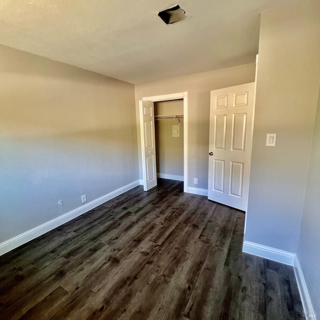 unfurnished bedroom featuring baseboards, a closet, and dark wood-style flooring