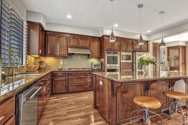 439 Mckenna Ct, Benicia, CA 94510 - kitchen featuring under cabinet range hood, stainless steel appliances, a sink, light wood-type flooring, and a kitchen bar