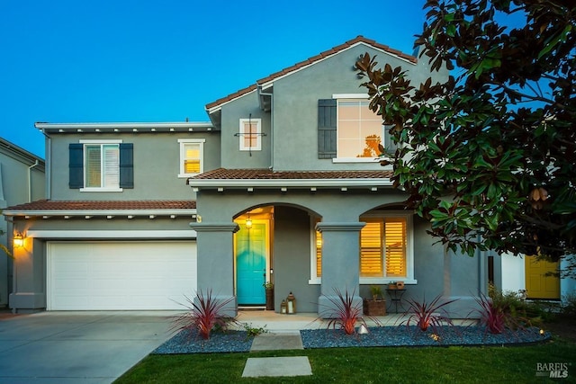 view of front of house with a tile roof, driveway, covered porch, an attached garage, and stucco siding