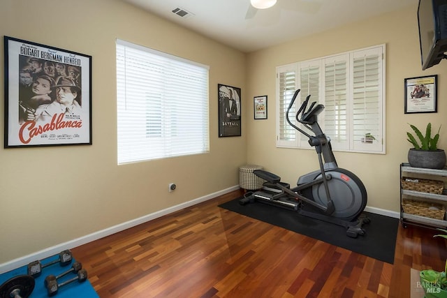 exercise area featuring baseboards, a ceiling fan, wood finished floors, and visible vents
