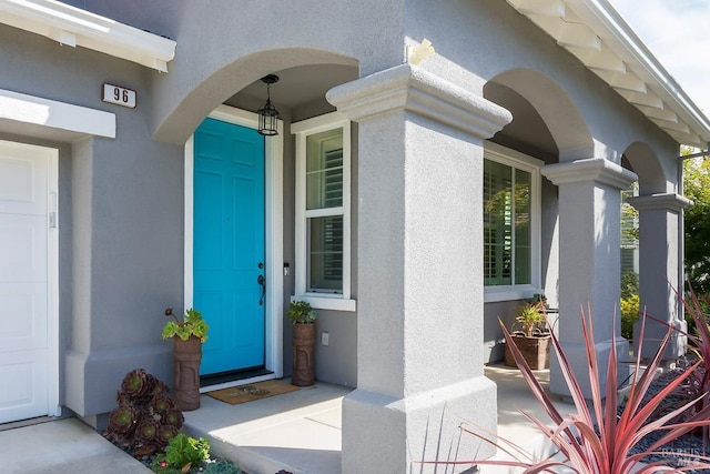 view of exterior entry featuring stucco siding and a porch