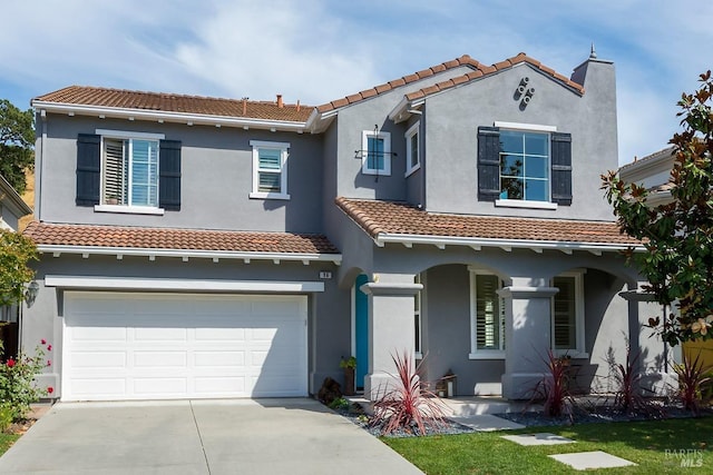 mediterranean / spanish home featuring a tiled roof, concrete driveway, an attached garage, stucco siding, and a porch