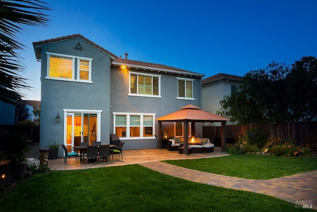 rear view of property featuring a gazebo, a patio area, a lawn, outdoor lounge area, and stucco siding