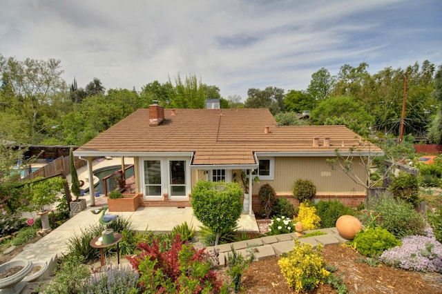 back of house featuring fence, a chimney, a patio, and brick siding