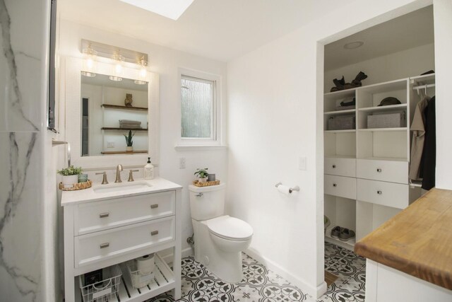 full bathroom with toilet, vanity, and baseboards