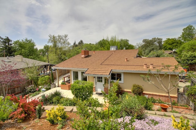 rear view of property featuring brick siding, fence, a patio area, and a chimney