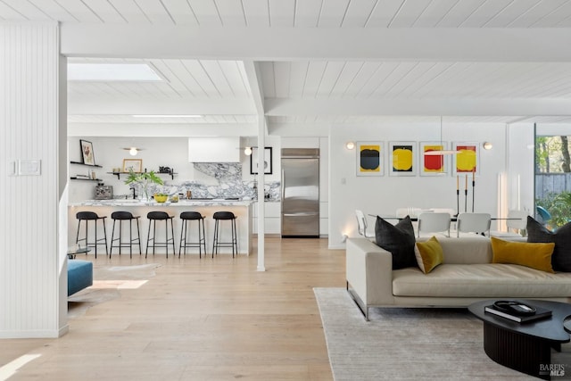 living area with beamed ceiling, light wood-type flooring, and wooden ceiling