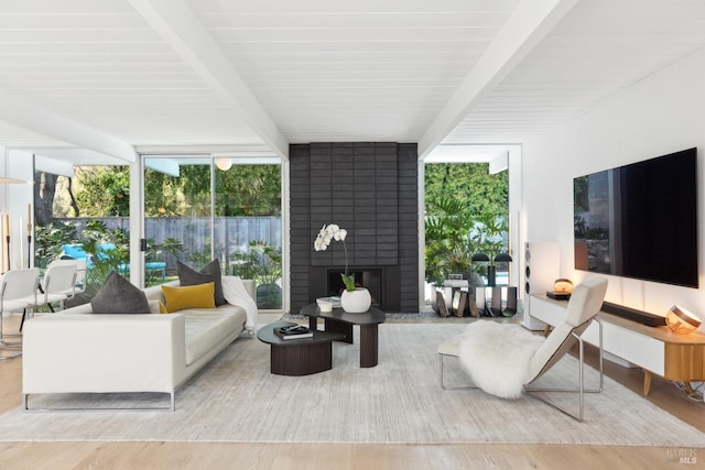living area with a brick fireplace, wood finished floors, beamed ceiling, and floor to ceiling windows