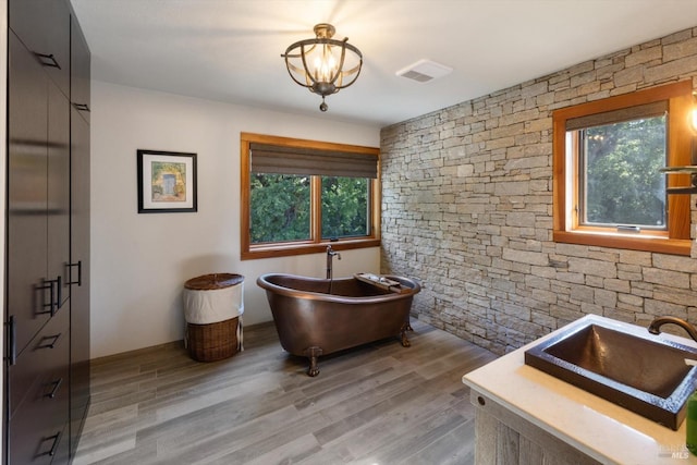 149 Auburn Way, Vacaville, CA 95688 - bathroom featuring a freestanding bath, an inviting chandelier, a sink, wood finished floors, and visible vents