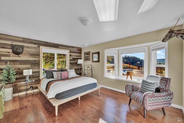 bedroom with wooden walls, wood finished floors, and baseboards