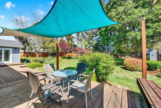 wooden deck with outdoor dining area, a lawn, and fence private yard