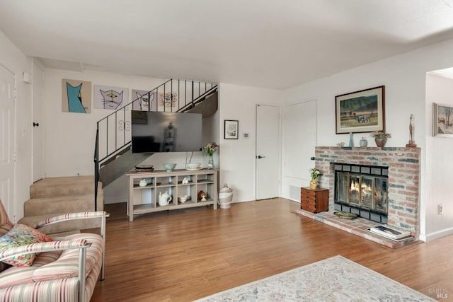 living area featuring stairs, wood finished floors, and a fireplace