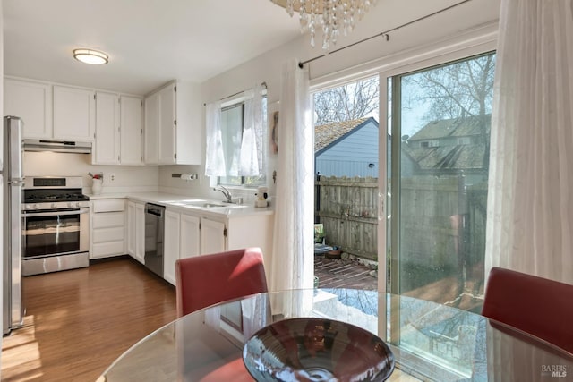 kitchen with light countertops, under cabinet range hood, white cabinets, a sink, and stainless steel appliances