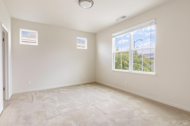 unfurnished room with visible vents, baseboards, and light carpet