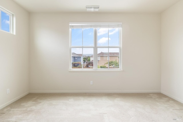 spare room featuring visible vents, baseboards, and light carpet