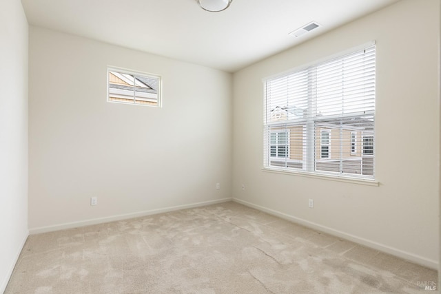 spare room with light colored carpet, baseboards, and visible vents