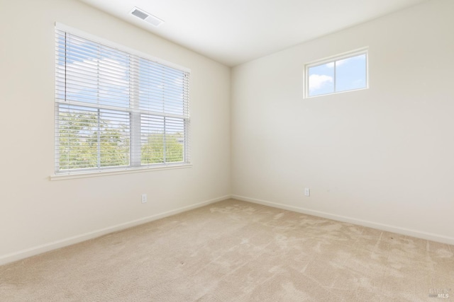 empty room featuring light carpet, baseboards, and visible vents