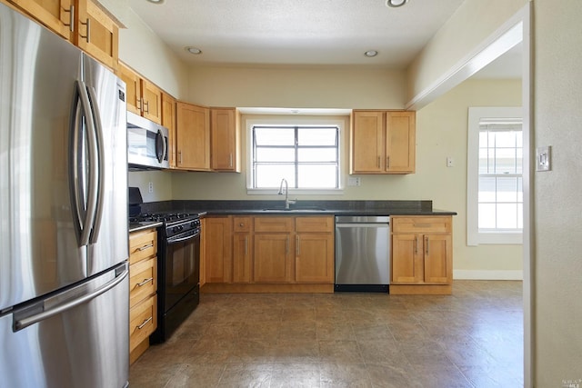 kitchen with dark countertops, a sink, recessed lighting, and appliances with stainless steel finishes