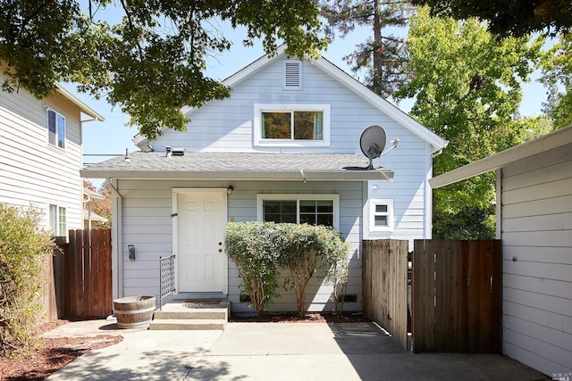 view of front of home featuring a patio area, a shingled roof, and fence