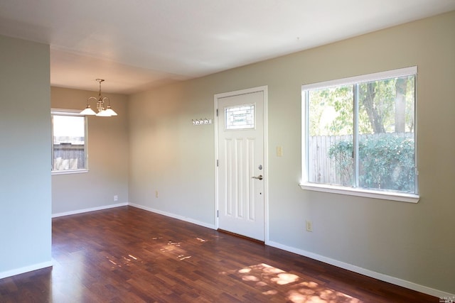 entrance foyer with dark wood finished floors, baseboards, and a notable chandelier