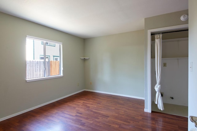 unfurnished bedroom featuring baseboards, wood finished floors, and a closet