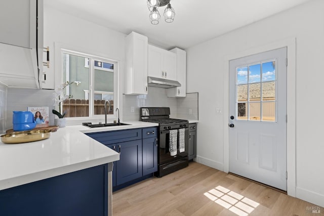 kitchen with a sink, decorative backsplash, black range with gas cooktop, light countertops, and under cabinet range hood