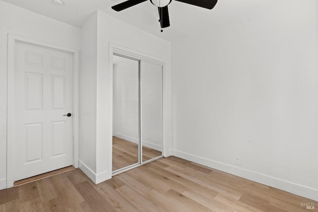 unfurnished bedroom featuring ceiling fan, baseboards, light wood finished floors, and a closet