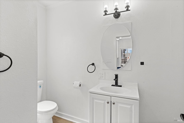 half bath with baseboards, toilet, vanity, and ornamental molding