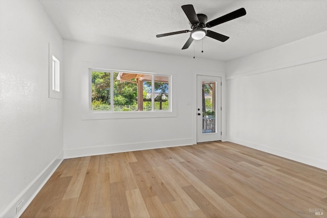 empty room featuring ceiling fan, baseboards, a textured ceiling, and light wood-type flooring