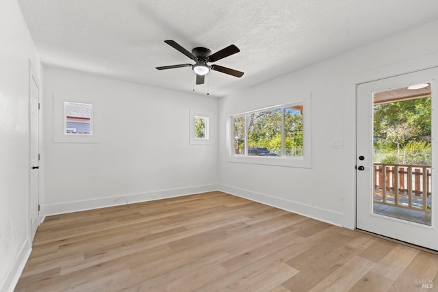 spare room featuring ceiling fan, baseboards, light wood-style floors, and plenty of natural light