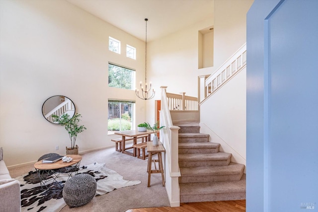 stairway featuring baseboards, a towering ceiling, and a chandelier