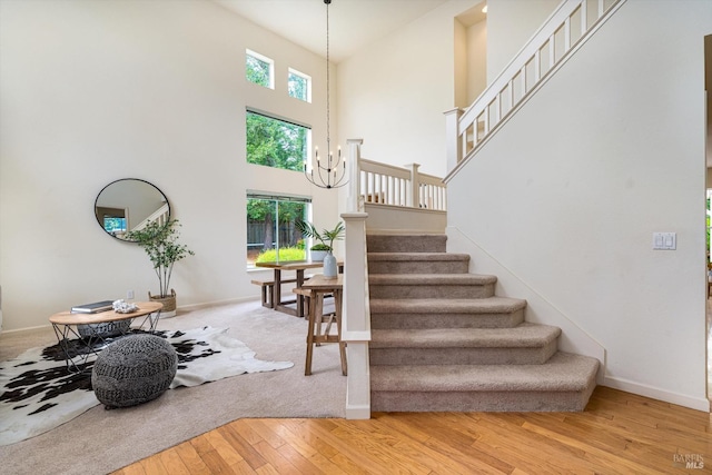 stairs featuring wood-type flooring, baseboards, a healthy amount of sunlight, and a towering ceiling