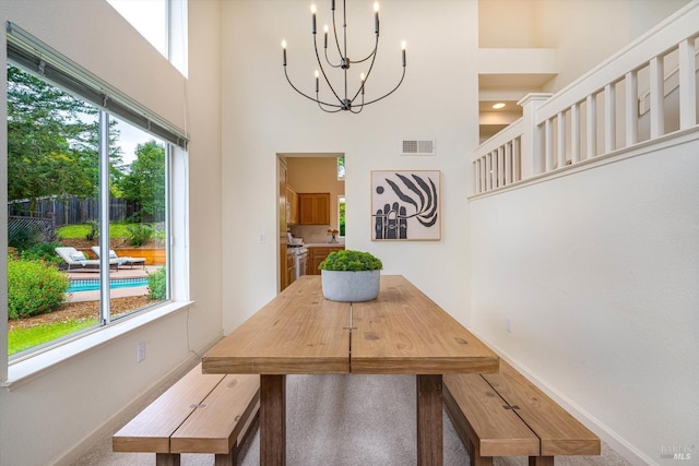 dining space with visible vents, baseboards, a high ceiling, and an inviting chandelier