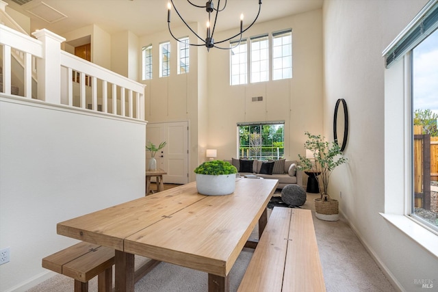 dining room featuring visible vents, baseboards, carpet, a notable chandelier, and a high ceiling
