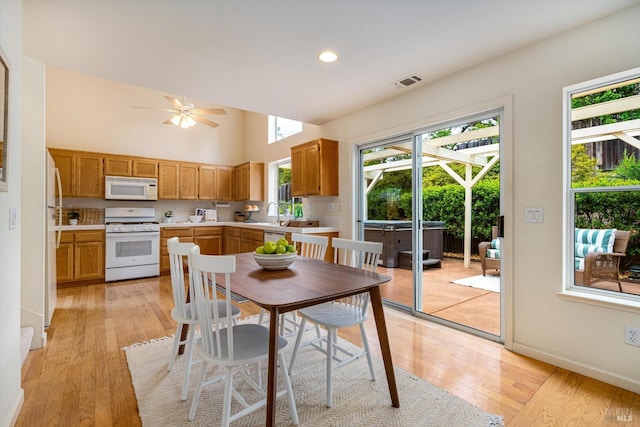 dining space featuring light wood-type flooring, visible vents, high vaulted ceiling, and ceiling fan
