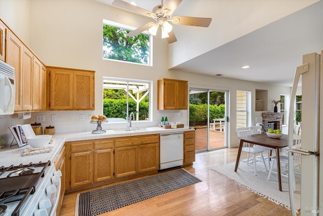 kitchen with tile countertops, a sink, white appliances, light wood-style flooring, and ceiling fan