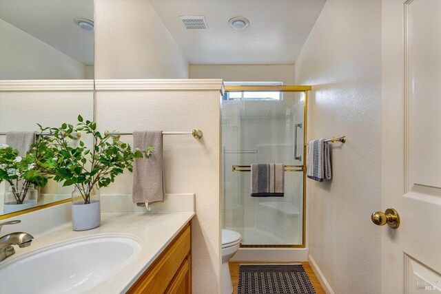 bathroom with toilet, vanity, visible vents, and a stall shower
